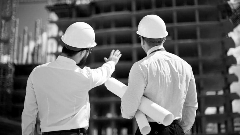 Two engineers in hard hats inspecting a building
